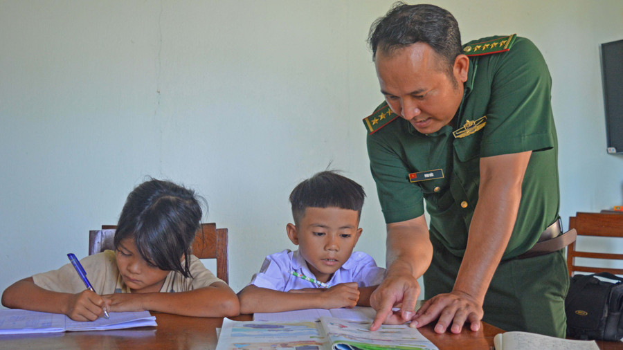 Đại úy Puih Đức hướng dẫn các em cách ghép vần. Ảnh: Anh Huy