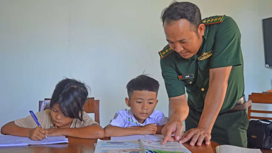 Đại úy Puih Đức hướng dẫn các em cách ghép vần. Ảnh: Anh Huy