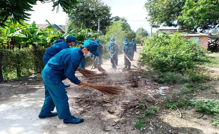 Lực lượng dân quân tự vệ giúp người dân dọn vệ sinh đường làng, ngõ xóm. Ảnh: Như Loan