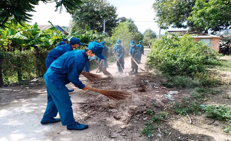 Lực lượng dân quân tự vệ giúp người dân dọn vệ sinh đường làng, ngõ xóm. Ảnh: Như Loan