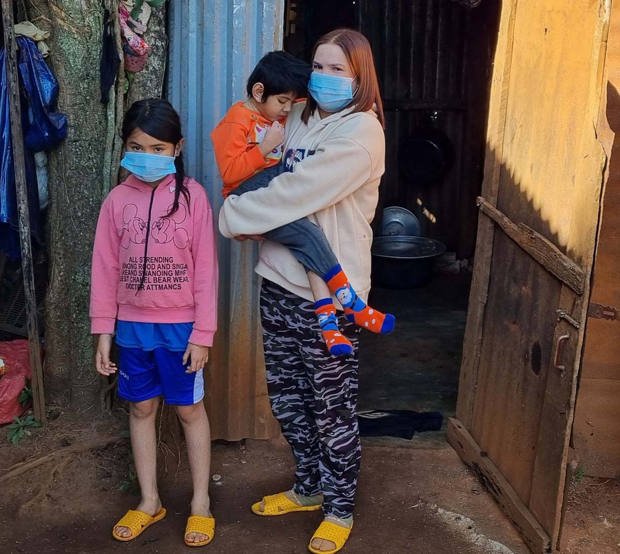 Chị Tanh cùng con bên căn nhà của gia đình. Ảnh: Hà Phương