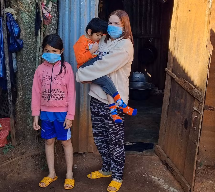 Chị Tanh cùng con bên căn nhà của gia đình. Ảnh: Hà Phương