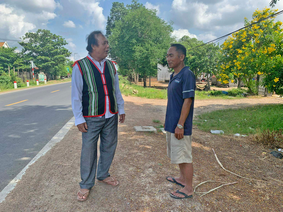 Ông Nay Dao (bìa trái) trao đổi công việc với người dân. Ảnh: R’Ô HOK