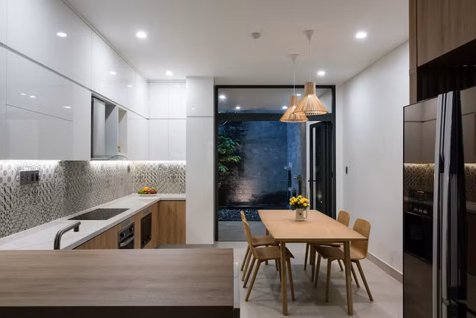  Phòng ăn và bếp được bố trí sau nhà với góc nhìn ra vườn trải sỏi, trồng lộc vừng.