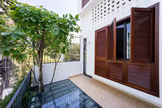 Khoảng rỗng phía trước nhà là sân để xe, sân chơi cho các bé với cây xanh tạo bóng mát. Phần ban công tầng 2 sử dụng kính để lấy sáng cho tầng dưới.