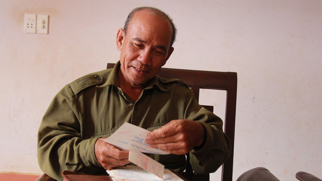 Ông Khôi lật dở các kỷ vật cũ thời trong quân ngũ.