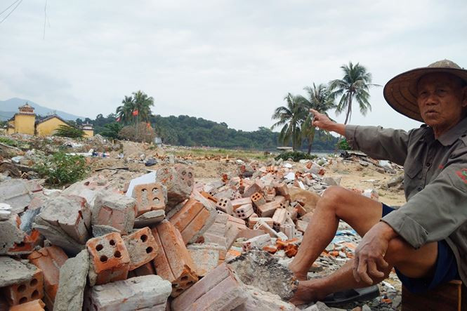 Ông lão làng Nam Ô Lê Sự chỉ tay về Dinh miếu linh thiêng của làng nay cũng sắp thành gạch vụn.