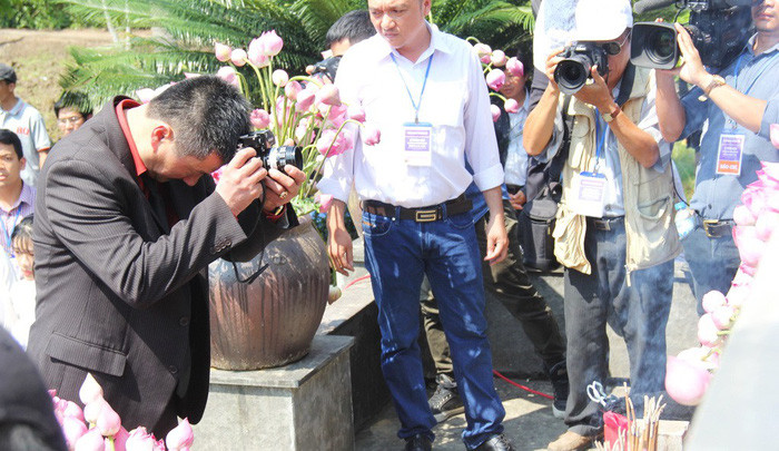 Ông Trần Văn Đức nâng chiếc máy ảnh Nikon F bái lạy trước tượng đài.