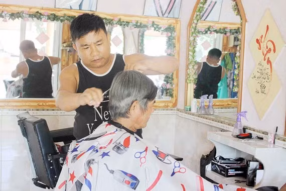 Anh Lê Minh Tân đang cắt tóc miễn phí cho một cụ già neo đơn Anh Lê Minh Tân đang cắt tóc miễn phí cho một cụ già neo đơn