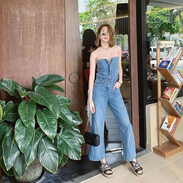 Thiều Bảo Trang khoe vai trần cuốn hút với thiết kế jumpsuit từ denim, có đường cúp ngực táo bạo. Cô nàng kết hợp item này với sandals của Chanel, túi xách nhỏ và kính mắt tráng gương thời thượng.