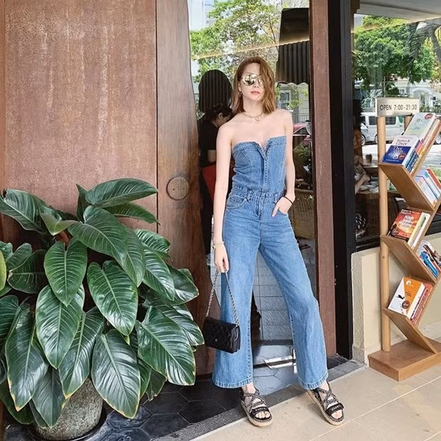 Thiều Bảo Trang khoe vai trần cuốn hút với thiết kế jumpsuit từ denim, có đường cúp ngực táo bạo. Cô nàng kết hợp item này với sandals của Chanel, túi xách nhỏ và kính mắt tráng gương thời thượng.