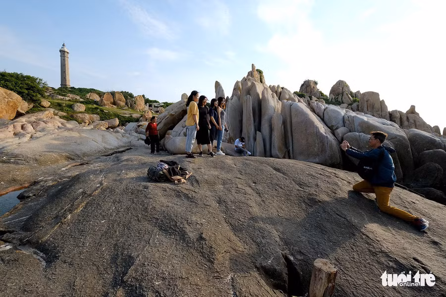 Du khách chụp ảnh lưu niệm với ngọn hải đăng Kê Gà trên đảo - Ảnh: NAM TRẦN