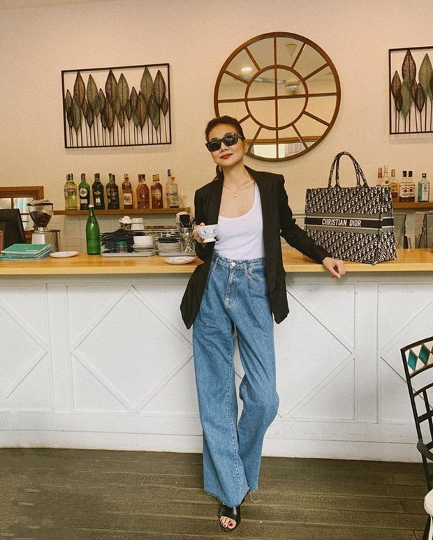 Blazer dáng rộng với gam màu tối giản yêu thích được Thanh Hằng mix ăn ý cùng áo tank trắng và quần denim ống loe. Siêu mẫu còn nâng tầm set đồ thành công nhờ chiếc túi Book Tote họa tiết oblique của Dior, có giá 2.700USD (khoảng 65 triệu đồng).