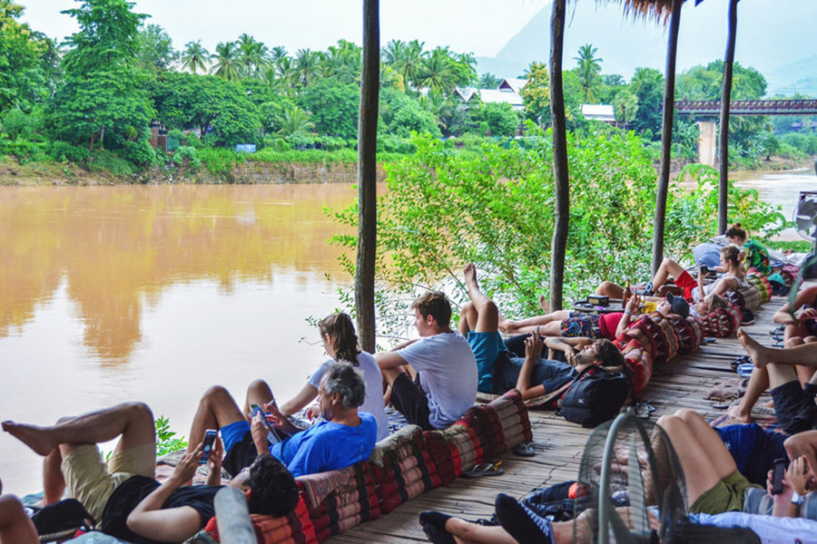  Khách du lịch lười biếng nằm dài bên bờ sông, uống bia Lào và 