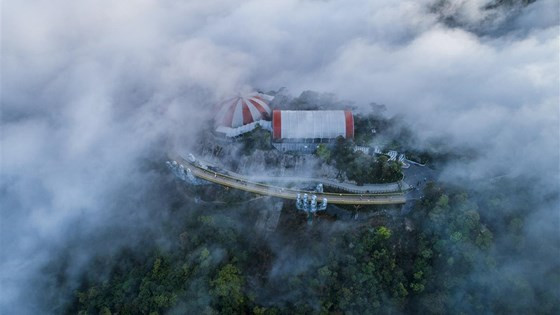 Bình minh xuyên qua màn mây dày đặc, đôi bàn tay nâng dải lụa vàng ẩn hiện huyền hoặc, dải cầu vàng ánh lên tia nắng đầu ngày
