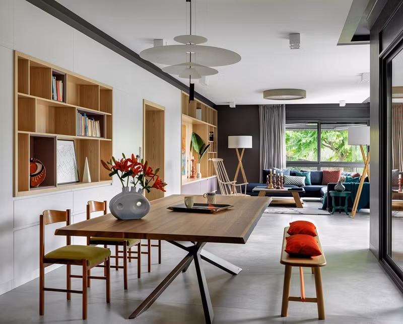 Căn phòng có bộ bàn ăn được kê sát với giá sách. Phía trước là bộ bàn ghế sofa dành cho việc tiếp khách. Nhìn toàn thể nhà ở trông rất thoáng đãng, gọn gàng. 