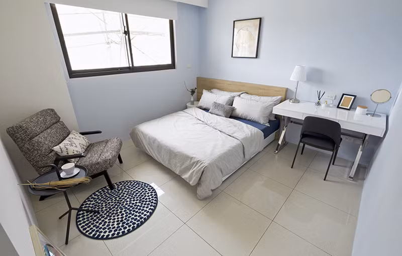 Phòng ngủ chính có thiết kế đơn giản, tập trung vào tính thực tế với một chiếc giường để ngủ, bàn làm việc và ghế thư giãn.