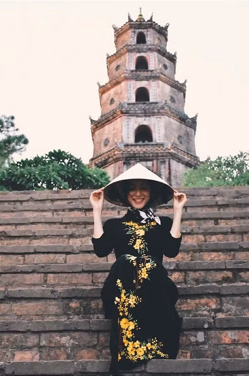 Trước đó, nữ diễn viên dừng chân ở Huế. Cô mặc áo dài sẫm màu thêu hoa vàng nổi bật khi vãn cảnh chùa Thiên Mụ.