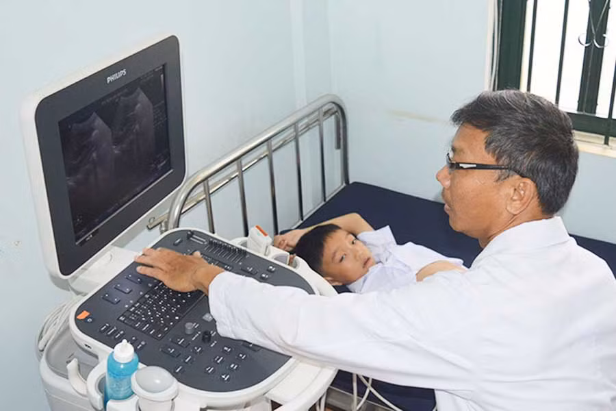  Bác sĩ Đào Phú Yên đang siêu âm cho một bệnh nhi. Ảnh: Phương Dung