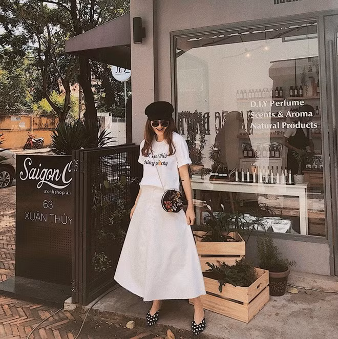 Chung ý tưởng mix đồ với cô chị, song Yến Nhi lại ưu ái gam màu nền nã hơn. Cô nàng kết hợp áo thun trắng với chân váy màu beige, điểm trang bằng mũ baker boy và chiếc túi tròn xinh xắn.