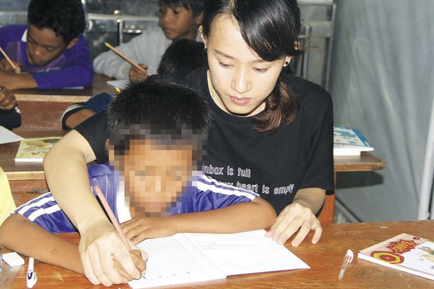 Các em nhỏ được cô giáo kèm cặp, tập viết những nét chữ đầu tiên.