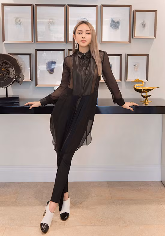  Trong một bức ảnh khác, nàng fashionista diện sơ mi dáng dài mỏng bằng voan đen kết hợp với chi tiết thân áo bằng lụa, quần tây skinny và đôi ankle bốt trắng đen.