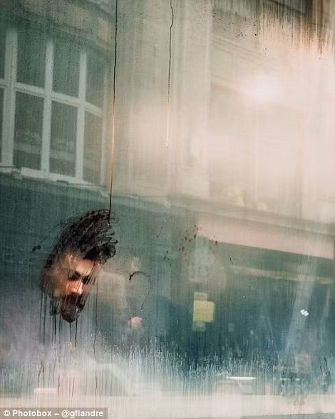  Một người đàn ông đang ngồi đọc sách phía sau cửa kính mờ hơi sương ở London.