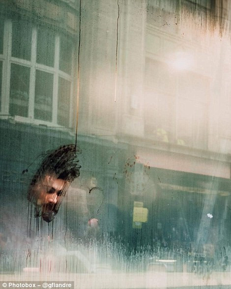  Một người đàn ông đang ngồi đọc sách phía sau cửa kính mờ hơi sương ở London.