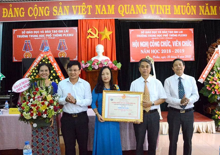 .Tiến sĩ Nguyễn Văn Long- Phó Giám đốc Sở Giáo dục- Đào tạo (thứ 2 trái sang) trao bằng công nhận trường đạt chuẩn quốc gia cho Trường THPT Pleiku. Ảnh: Minh Vỹ
