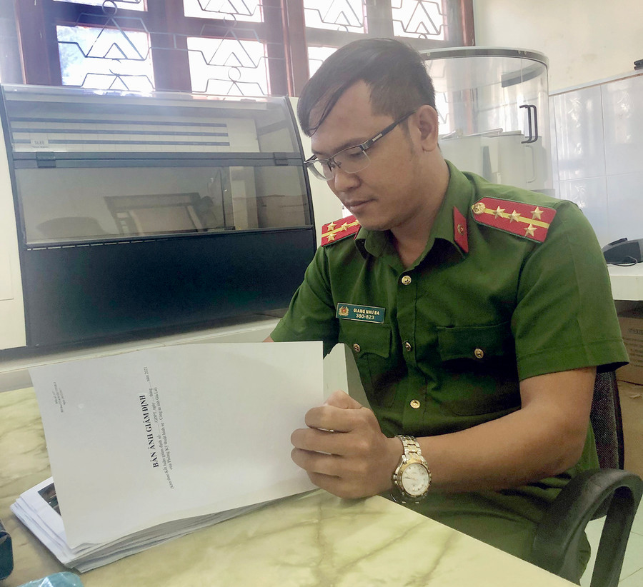 Bác sĩ-Đại úy Giang Như Ba nghiên cứu bản ảnh giám định pháp y. Ảnh: Thúy Trinh