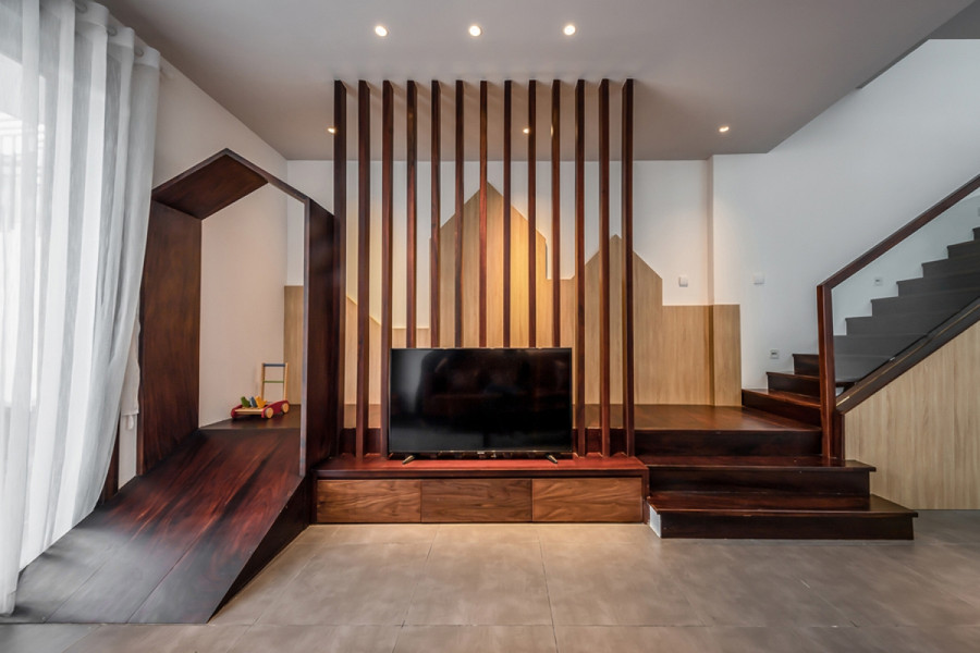 Một giải pháp thú vị ở phòng khách: Kệ tivi không kê sát tường như thường thấy mà được kéo gần về phía sofa, để không bị quá xa. Khoảng trống phía sau được thiết kế thành nơi vui đùa cho trẻ; và cũng là lối giao thông đi từ cầu thang xuống không cắt qua khu vực sofa – tivi nếu như có người đang ngồi xem. Một giải pháp thú vị ở phòng khách: Kệ tivi không kê sát tường như thường thấy mà được kéo gần về phía sofa, để không bị quá xa. Khoảng trống phía sau được thiết kế thành nơi vui đùa cho trẻ; và cũng là lối giao thông đi từ cầu thang xuống không cắt qua khu vực sofa – tivi nếu như có người đang ngồi xem.