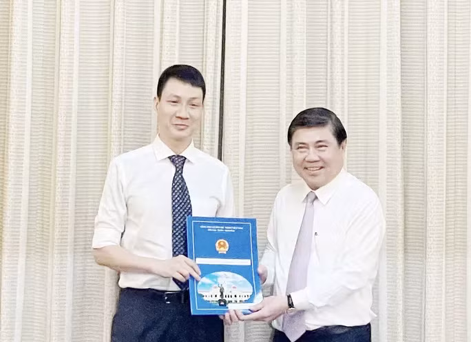 Chủ tịch UBND TP Nguyễn Thành Phong (bìa phải) trao quyết định cho ông Trương Trung Kiên