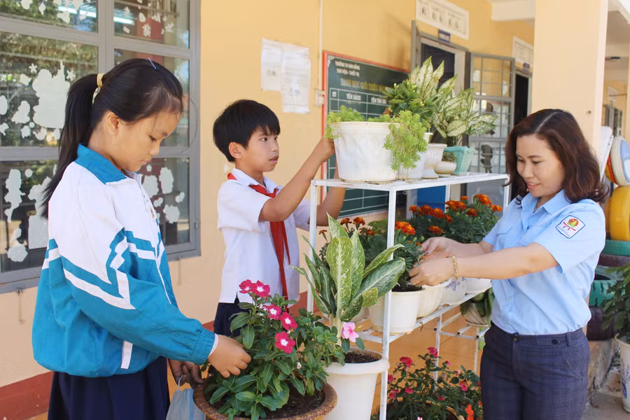 Cô Nguyễn Thúy Hằng cùng các em học sinh chăm sóc hoa và cây xanh trong trường học. Ảnh: Phan Lài