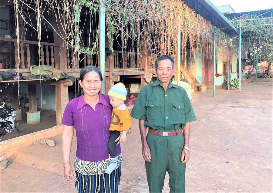 Thương binh Hôi cùng vợ và cháu bên căn nhà sàn kiên cố, rộng rãi. Ảnh: Đinh Yến
