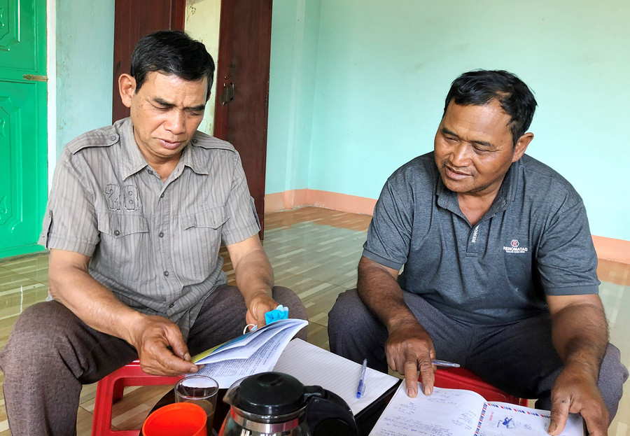 Ông Blâm (bìa phải) trao đổi công việc với cán bộ Ban Công tác Mặt trận thôn. Ảnh: Anh Huy