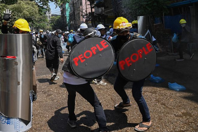 Người biểu tình dùng khiên che chắn trong một cuộc xuống đường tại Yangon, Myanmar - ảnh: AFP