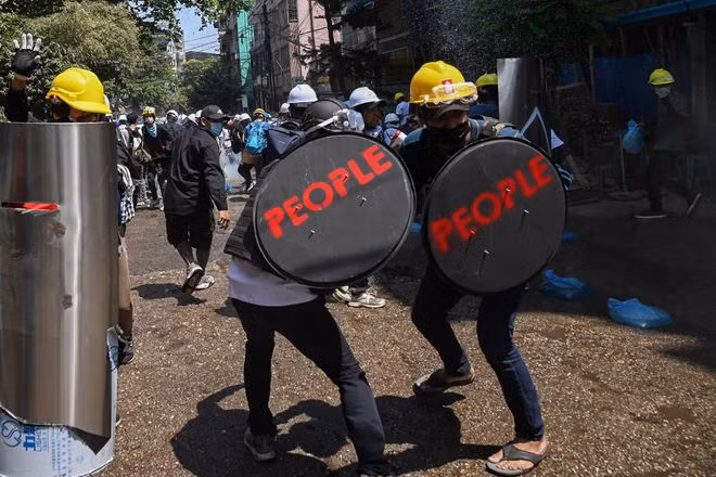 Người biểu tình dùng khiên che chắn trong một cuộc xuống đường tại Yangon, Myanmar - ảnh: AFP