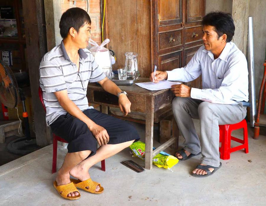 Ông Nguyễn Tiến Xuân (bìa phải)-Trưởng thôn 3, xã Thành An, thị xã An Khê đến từng nhà rà soát, lập danh sách cử tri trong thôn. Ảnh: Ngọc Minh