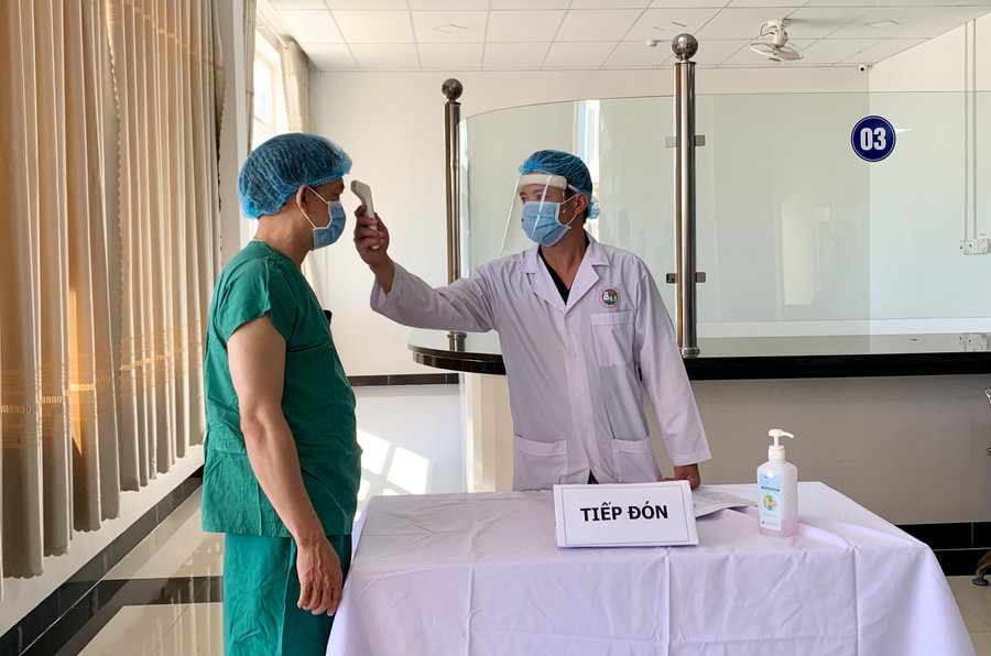 Nhân viên y tế đo thân nhiệt trước khi tiêm chủng. Ảnh: Như Nguyện  Nhân viên y tế đo thân nhiệt trước khi tiêm chủng. Ảnh: Như Nguyện