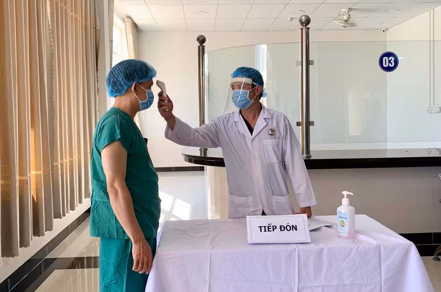  Nhân viên y tế đo thân nhiệt trước khi tiêm chủng. Ảnh: Như Nguyện