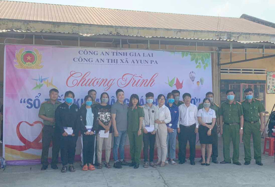 Đại diện lãnh đạo Công an thị xã Ayun Pa, nhà tài trợ trao sổ tiết kiệm cho các em học sinh nghèo hiếu học. Ảnh.Vũ Chi