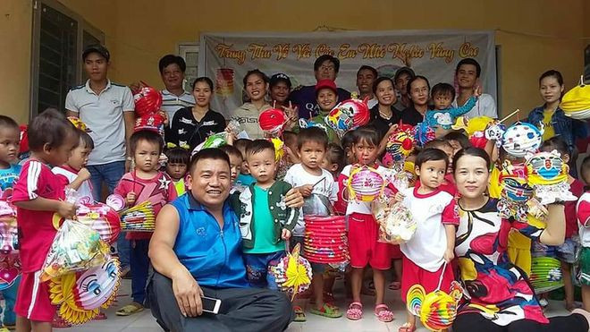 Anh Lê Minh Tân (người cầm điện thoại) trong một lần mang quà đến cho trẻ em vùng cao - Ảnh: NVCC