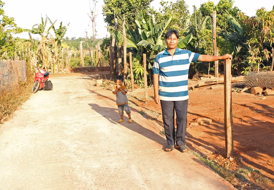 Ông Rmah Luên (làng Bê Tel, xã Ia Rong, huyện Chư Pưh) bên con đường được bê tông hóa chạy qua nhà. Ảnh: Nguyễn Diệp