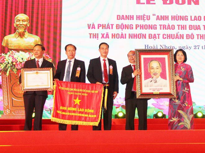 Phó chủ tịch nước Đặng Thị Ngọc Thịnh (bìa phải) trao danh hiệu Anh hùng lao động thời kỳ đổi mới cho TX.Hoài Nhơn. ẢNH: HOÀNG TRỌNG