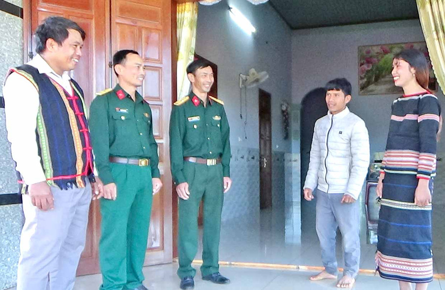 Ông Rơ Châm Bái (bìa trái) và cán bộ Công ty Bình Dương nói chuyện với người dân làng Blu. Ảnh: Sơn Tùng