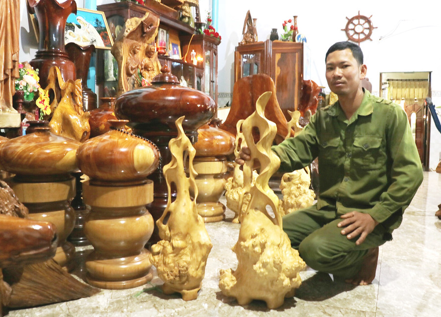 Anh Quách Văn Lâm (xã Bờ Ngoong, huyện Chư Sê) giới thiệu về những chiếc lộc bình làm bằng gốc cà phê. Ảnh: Nhật Hào