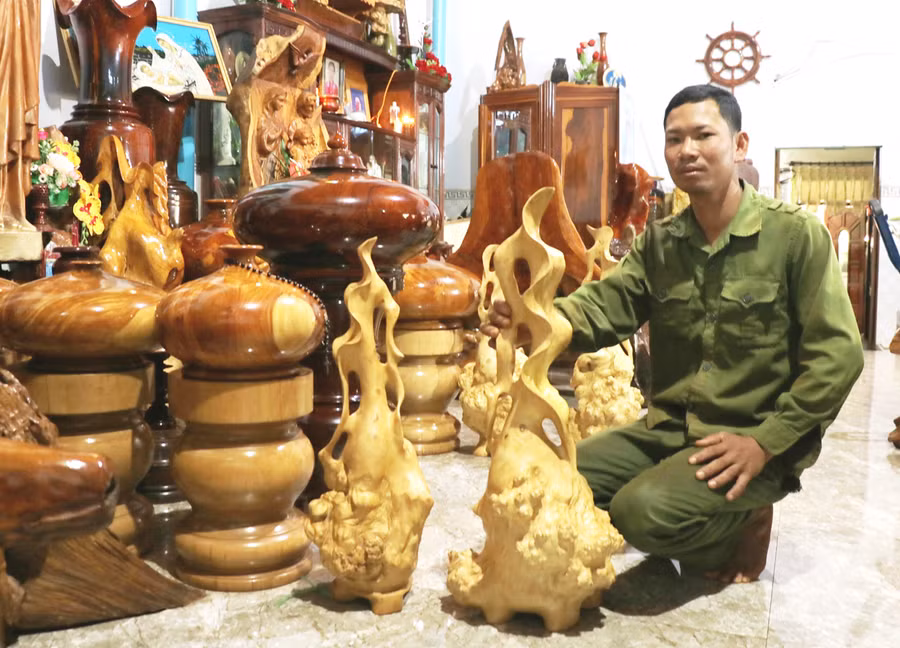 Anh Quách Văn Lâm (xã Bờ Ngoong, huyện Chư Sê) giới thiệu về những chiếc lộc bình làm bằng gốc cà phê. Ảnh: Nhật Hào