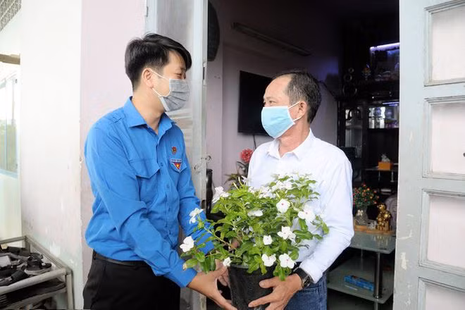 Thanh niên tình nguyện tặng cây xanh, hoa kiểng cho người dân tại chung cư Lò Gốm (Q.6) - Ảnh: Lê Thanh