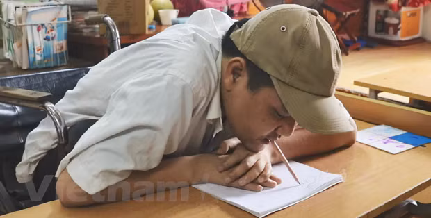 Anh Phùng Văn Trường viết chữ bằng miệng. (Ảnh: PV/Vietnam+)