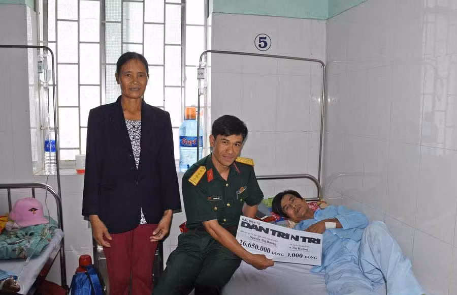 Đại diện Bệnh viện Quân y 211 trao tiền giúp đỡ cho gia đình bà Hướng. Ảnh: Hà Phương